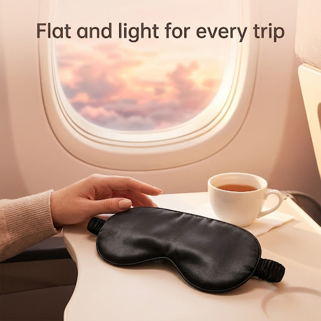 Black satin sleep mask on an airplane tray table